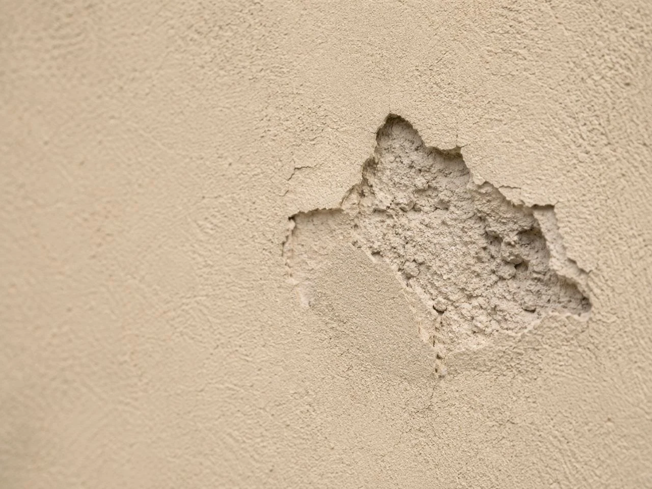 Close-up example of chipped and impact-damaged stucco